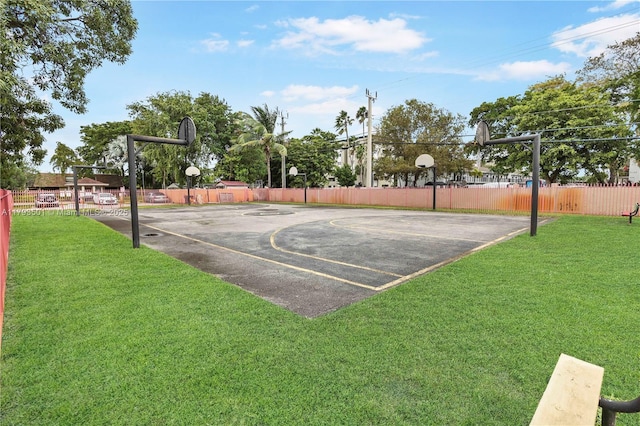 view of sport court featuring a yard, fence, and basketball hoop