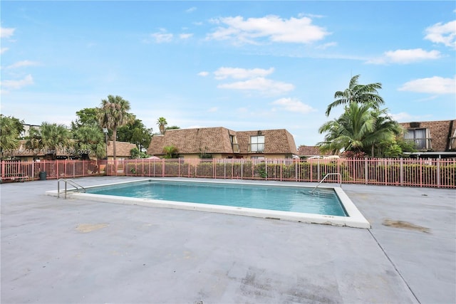 community pool with a patio area and fence