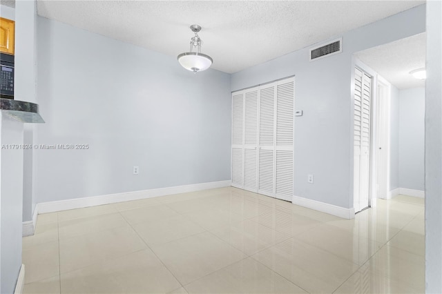 unfurnished bedroom featuring baseboards, a closet, a textured ceiling, and visible vents