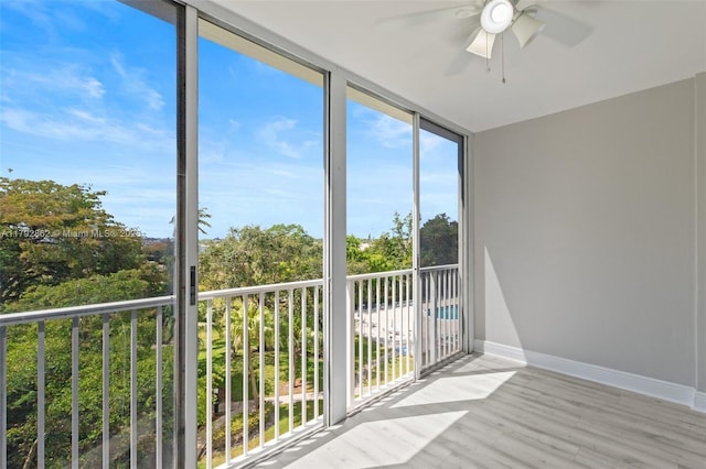 unfurnished sunroom with baseboards, floor to ceiling windows, and wood finished floors