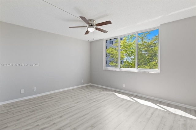 spare room with baseboards, a textured ceiling, light wood finished floors, and ceiling fan