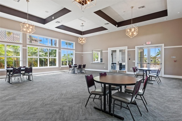 dining space with carpet floors, a high ceiling, french doors, and a notable chandelier
