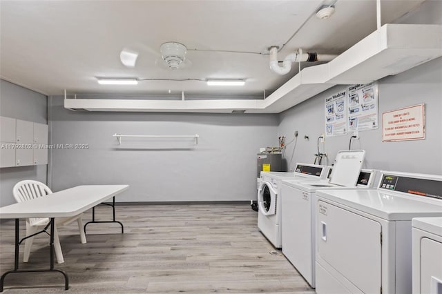 community laundry room featuring separate washer and dryer and light wood-style flooring