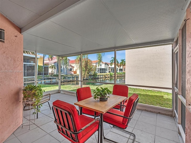 sunroom / solarium with a residential view, outdoor dining space, a water view, and a wealth of natural light