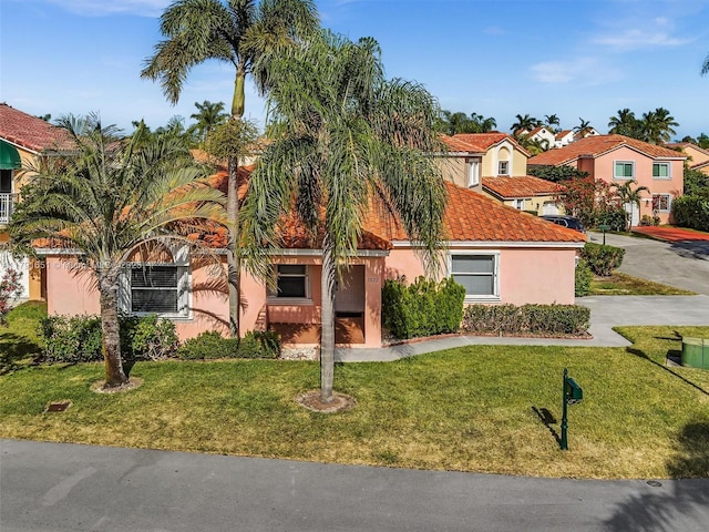mediterranean / spanish-style house featuring stucco siding, a front yard, and a tile roof