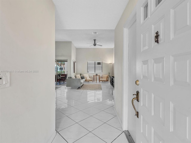 foyer featuring baseboards, ceiling fan, visible vents, and light tile patterned floors