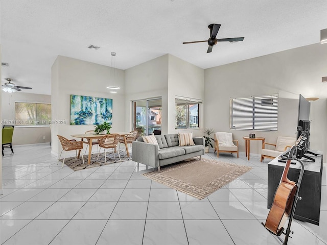 living room featuring baseboards, visible vents, a ceiling fan, and a wealth of natural light
