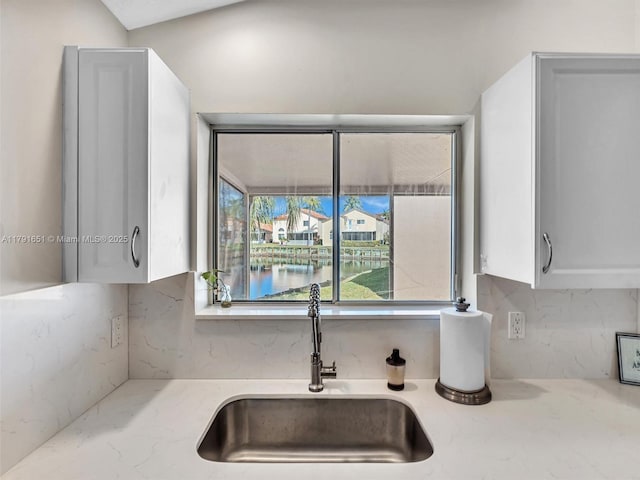 kitchen with light stone counters, a sink, and tasteful backsplash