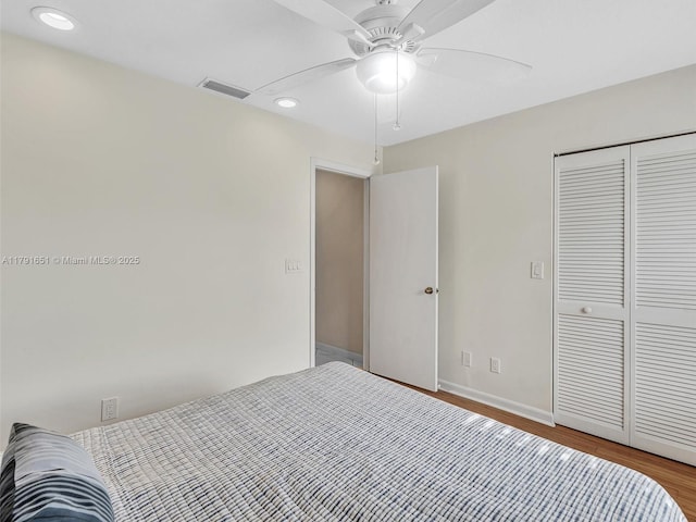 bedroom with recessed lighting, baseboards, wood finished floors, visible vents, and a closet