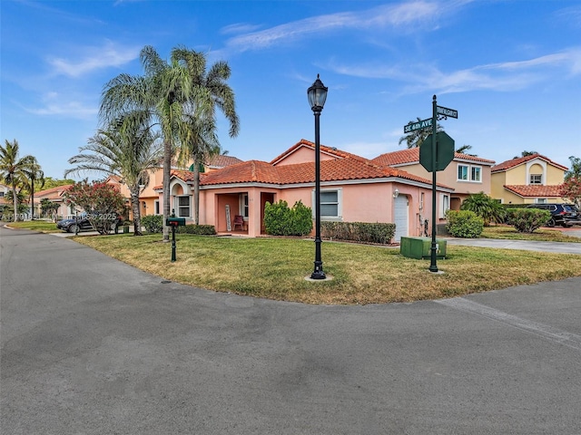 view of front of home featuring a garage, a front yard, stucco siding, concrete driveway, and a tile roof