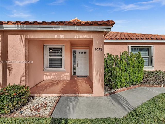 doorway to property with stucco siding and a tiled roof