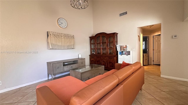living area featuring baseboards, visible vents, light tile patterned floors, and a towering ceiling
