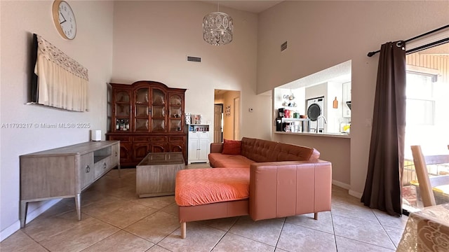 sitting room with visible vents, baseboards, a towering ceiling, and light tile patterned floors