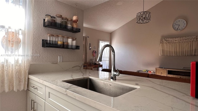 kitchen with a textured wall, open shelves, a sink, a textured ceiling, and lofted ceiling