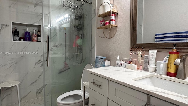 bathroom with vanity, a marble finish shower, a textured wall, and toilet