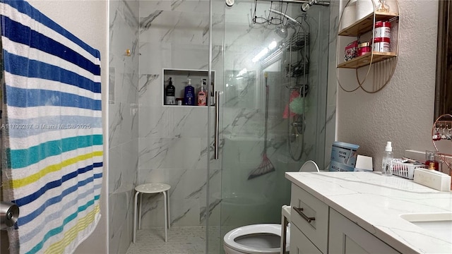 full bath featuring a marble finish shower, a textured wall, vanity, and toilet