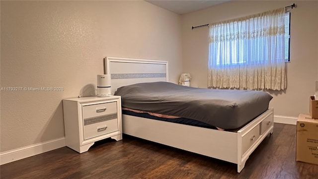 bedroom with baseboards, a textured wall, and dark wood finished floors
