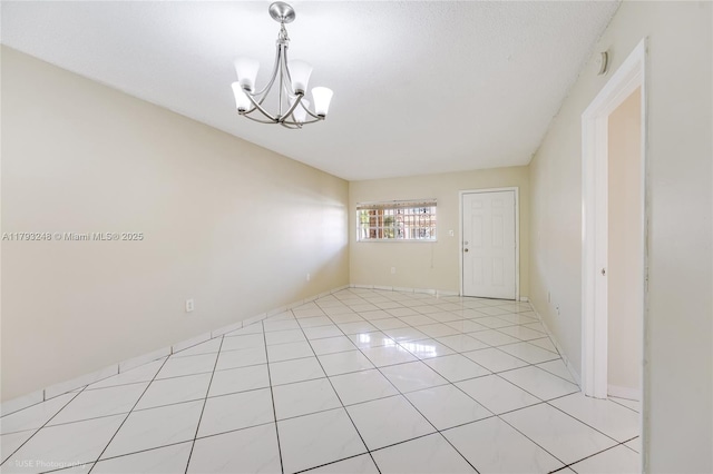 spare room featuring light tile patterned floors and a notable chandelier