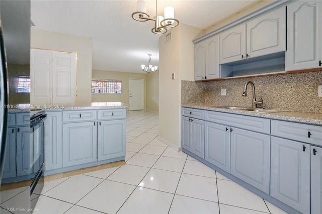 kitchen featuring hanging light fixtures, a sink, light countertops, a chandelier, and tasteful backsplash