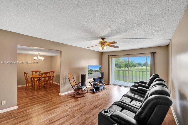 living area with a textured ceiling, baseboards, ceiling fan with notable chandelier, and light wood-type flooring