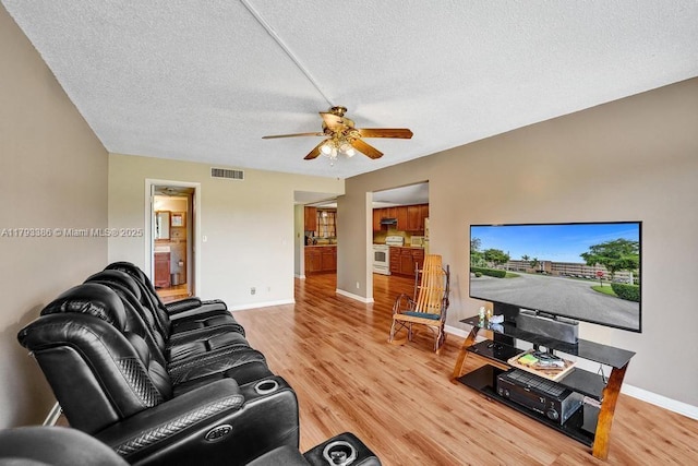 living room with ceiling fan, a textured ceiling, visible vents, wood finished floors, and baseboards