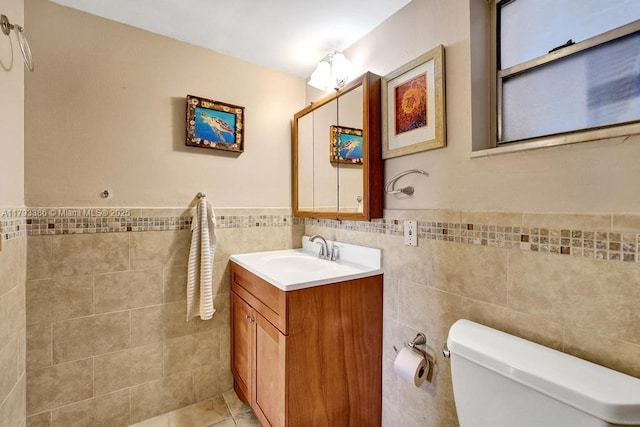 bathroom featuring toilet, tile walls, wainscoting, and vanity