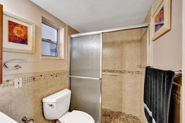 bathroom featuring toilet, tile walls, wainscoting, and a stall shower