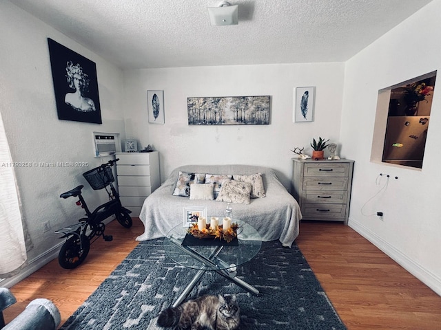 bedroom with a textured ceiling, baseboards, and wood finished floors