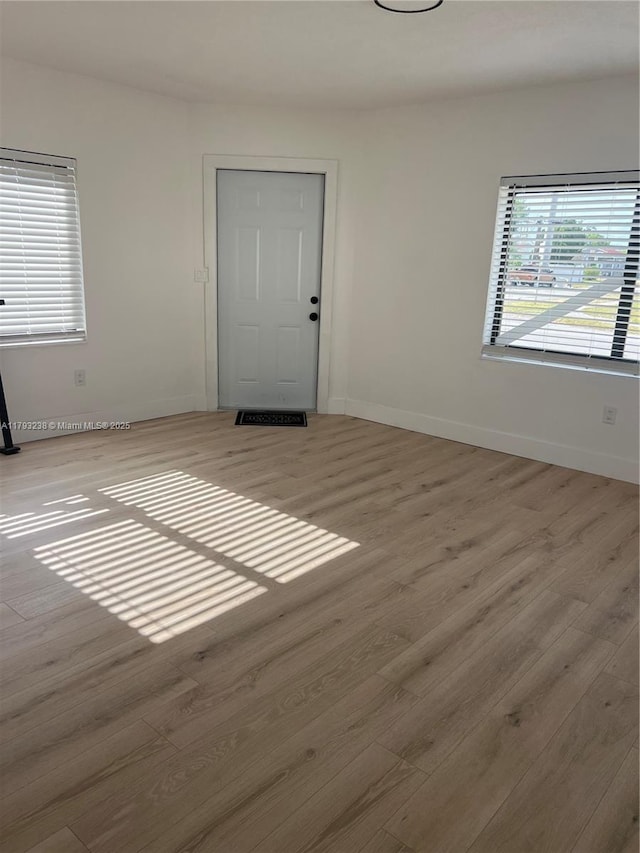 spare room with baseboards and wood finished floors
