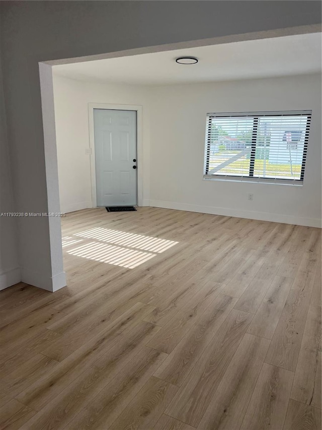 unfurnished room featuring baseboards and light wood finished floors