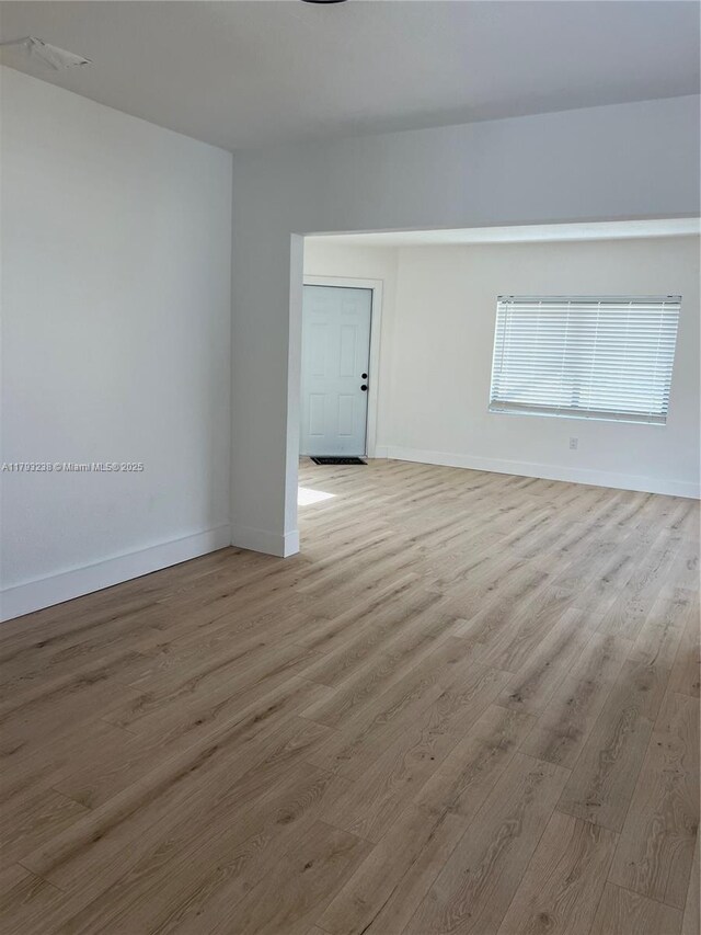 unfurnished room featuring baseboards and light wood finished floors