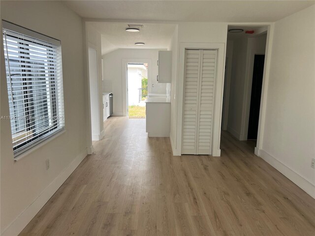 hall with baseboards and light wood finished floors