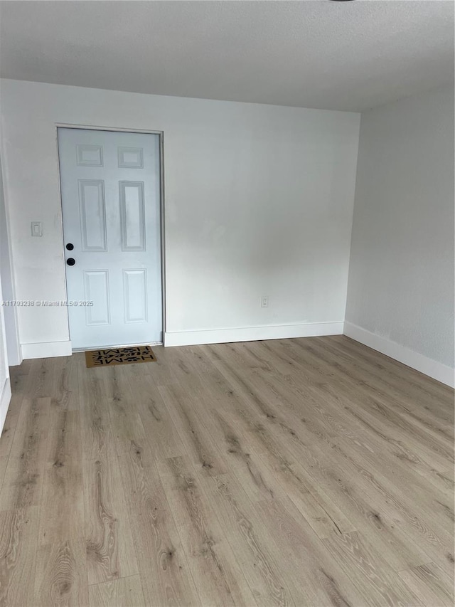 spare room with baseboards and wood finished floors
