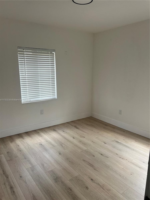 spare room with baseboards and wood finished floors