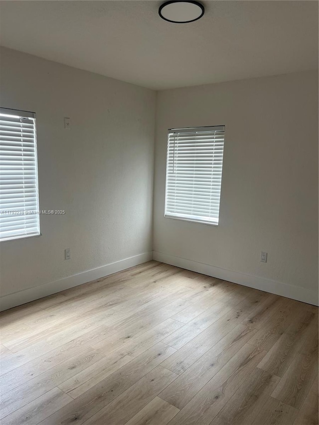 unfurnished room with baseboards and wood finished floors