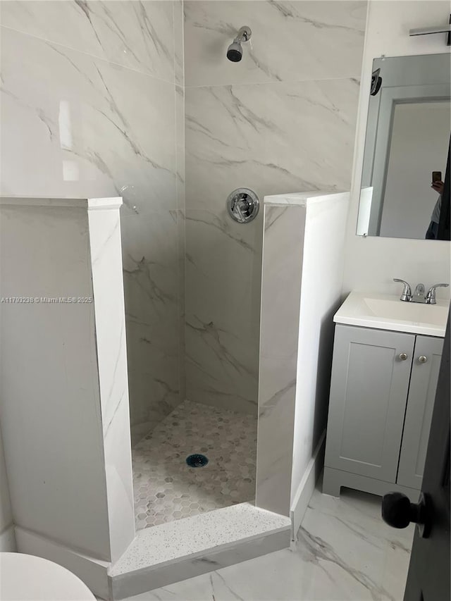 full bathroom featuring vanity, marble finish floor, a marble finish shower, and toilet