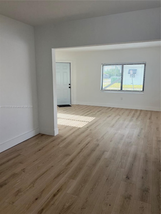 spare room featuring baseboards and wood finished floors