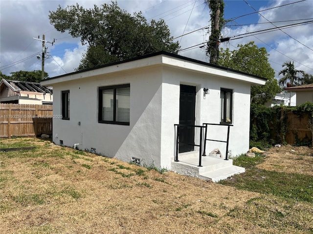 exterior space featuring fence, stucco siding, and a yard