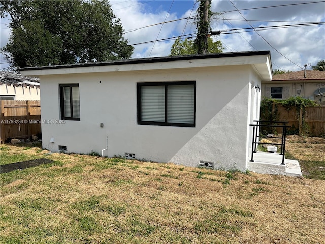 view of side of home featuring fence, stucco siding, a yard, and crawl space