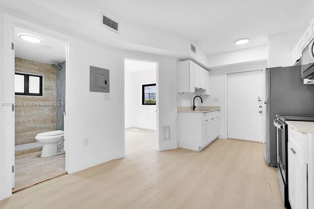 1814 NW 2nd Ct, Miami, FL 33136 - kitchen with electric stove, a sink, electric panel, light wood-style floors, and light countertops