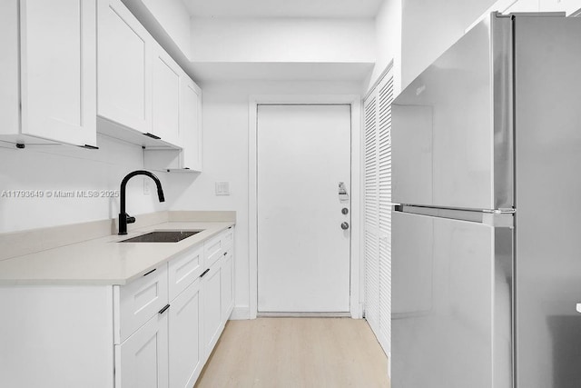 1814 NW 2nd Ct, Miami, FL 33136 - kitchen with freestanding refrigerator, a sink, light wood finished floors, white cabinetry, and light countertops
