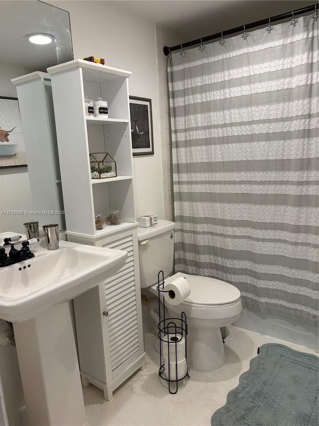 bathroom featuring toilet, curtained shower, and a sink