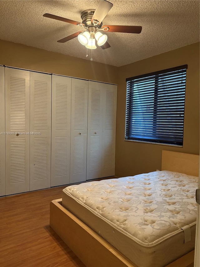 bedroom with a ceiling fan, a closet, a textured ceiling, and wood finished floors