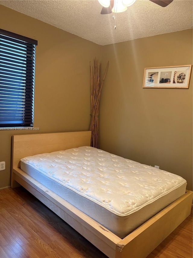 bedroom featuring ceiling fan, a textured ceiling, and wood finished floors