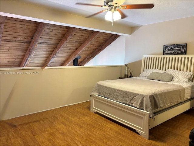 bedroom with lofted ceiling with beams, ceiling fan, and wood finished floors