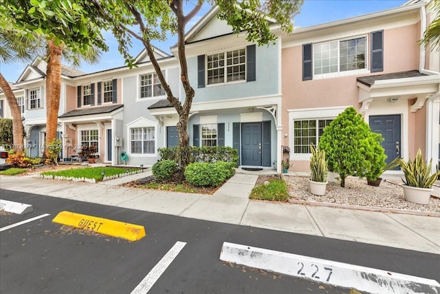 view of property with uncovered parking and stucco siding