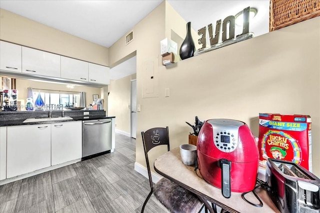 kitchen with stainless steel dishwasher, white cabinetry, visible vents, and a sink