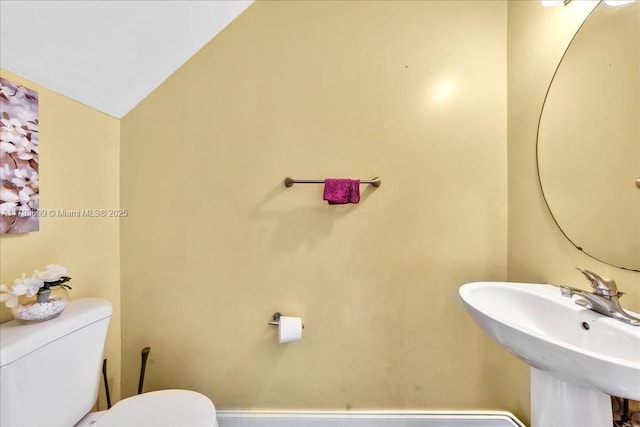 bathroom featuring a sink, vaulted ceiling, and toilet
