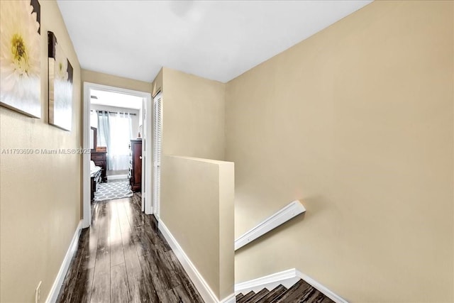 hall with baseboards, an upstairs landing, and dark wood-style floors