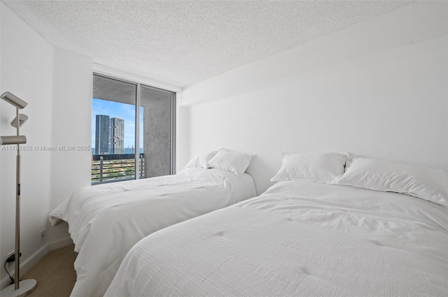 19101 NE 36th Ct Unit 2509, Aventura, FL 33180 - bedroom with a wall of windows, a textured ceiling, access to exterior, baseboards, and carpet flooring